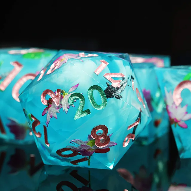 Close-up of aqua-blue D20 with lotus flowers, fish and glittering numerals.