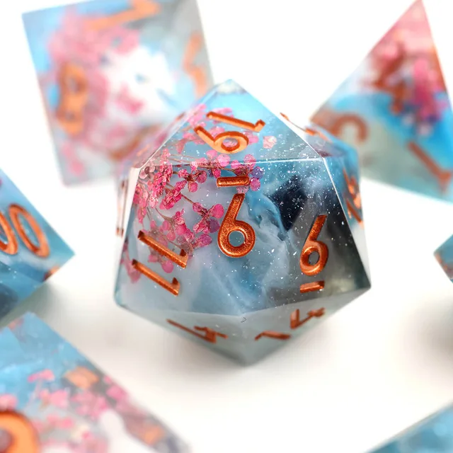 Close-up of a blue and clear floral D20 with copper-orange numbers.