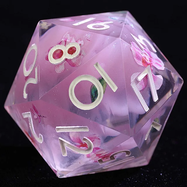 Close-up of a translucent pink D20 with blossoms, green leaves, and pale numerals.