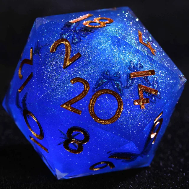 Close-up of a glittery blue D20 with copper-gold numbers and dark butterfly details.