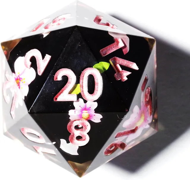 Close-up of a black and clear D20 with pink numbers and cherry blossoms.