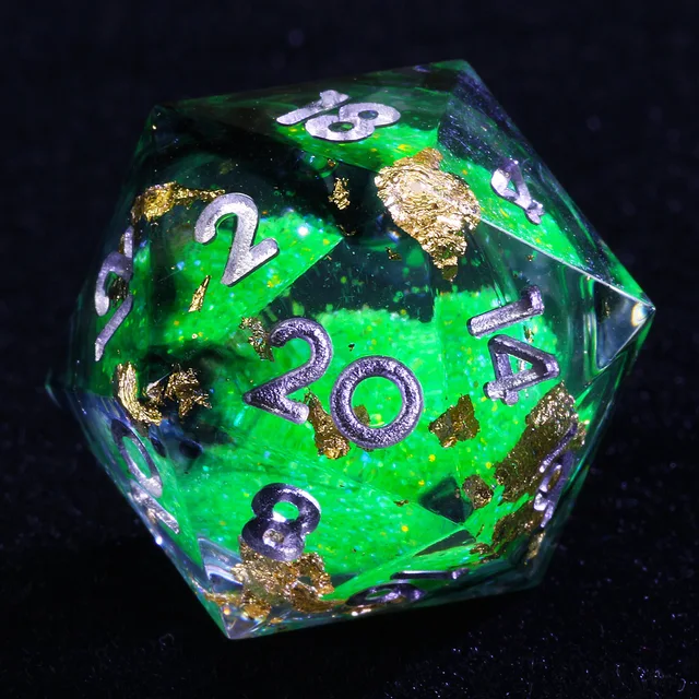 Close-up of a clear green-core D20 with gold-coloured flakes and silver-coloured numbers.