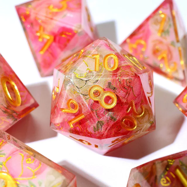 Close-up of a pink-red floral twenty-sided die with gold-coloured numbers
