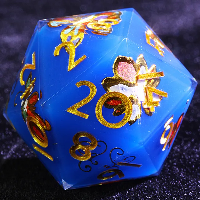 Close-up of a blue D20 with gold numbers and multicoloured floral artwork.