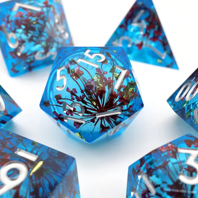 Close-up of a blue die with red branching flowers and silver numbers.