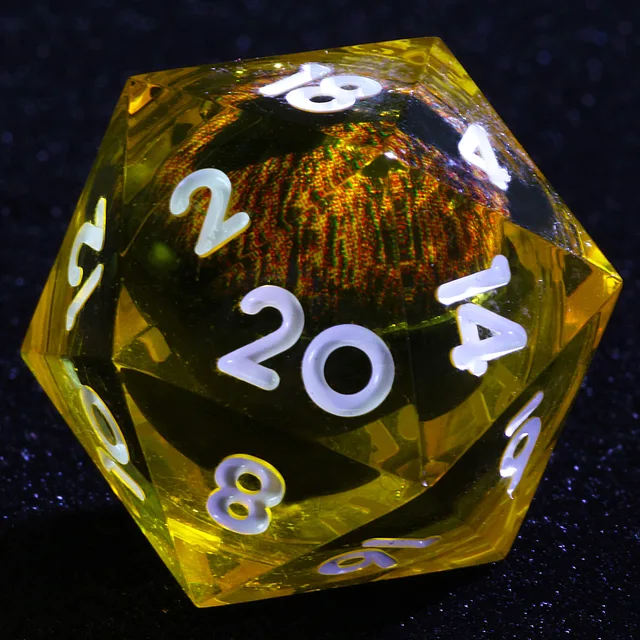 Close-up of a yellow D20 with white numbers and an eye-like core.