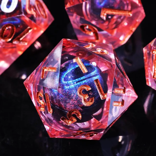 Close-up of a sharp-edged pink-red die with a shimmering blue-purple core and copper-orange numbers.