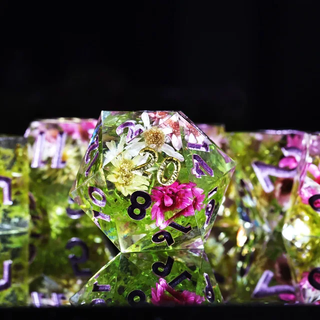 Close-up of a clear floral D20 with green tones and purple and gold numbers.