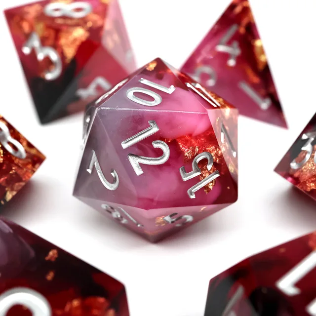 Close-up of a pink and crimson D20 with gold flecks and silver numbers.