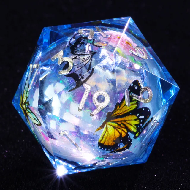 Close-up of a transparent blue D20 with silver numbers and yellow and dark butterfly designs.