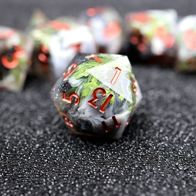 Close-up of a D20 with green inclusions, cloudy dark and white swirls, and red numbers.