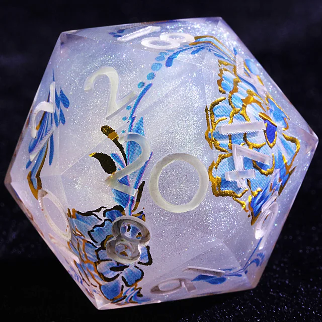 Close-up of a pale blue shimmering D20 with blue flowers, gold outlines, and white numerals.