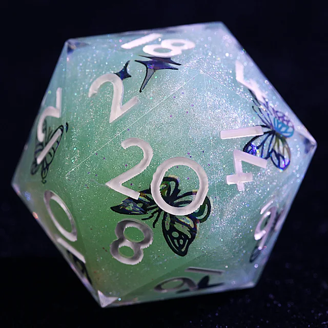 Close-up of a teal glitter D20 with white numerals and iridescent butterfly designs.