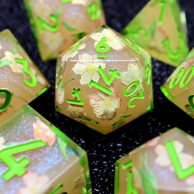 Close-up of a green-numbered D20 with pale flowers inside.