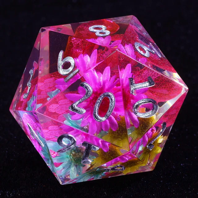 Close-up of a clear D20 with pink flowers, red petals and silver-coloured numbers.