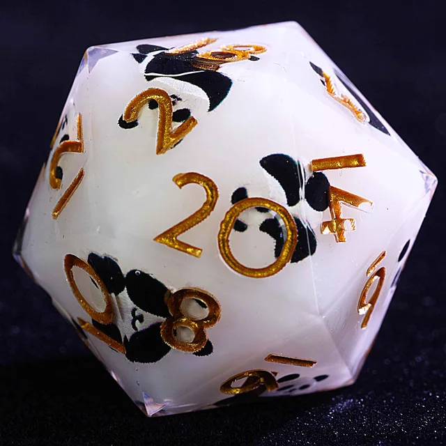 Close-up of a white panda-patterned D20 with gold numbers.