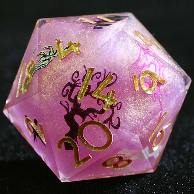 Close-up of a glittery pink D20 with gold numbers and a black bare-tree illustration.
