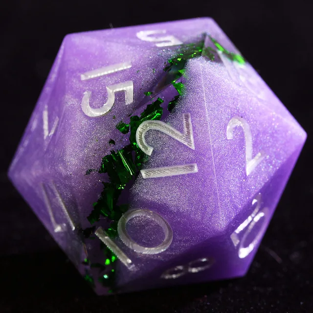 Close-up of a purple twelve-sided die with green foil and pale numerals.