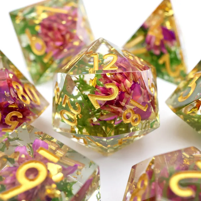 Close-up of a clear D20 with a purple flower, green inclusions and gold numbers.