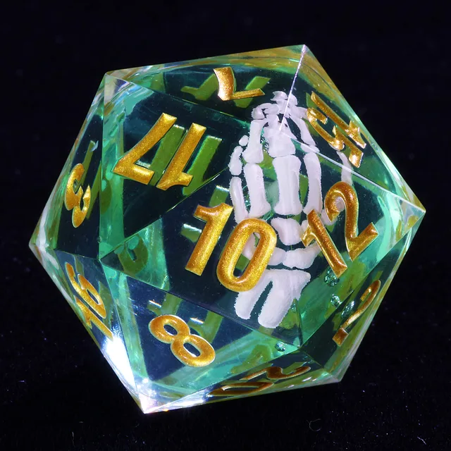 Close-up of a clear teal-green D20 with gold numbers and a white skeletal hand inside.