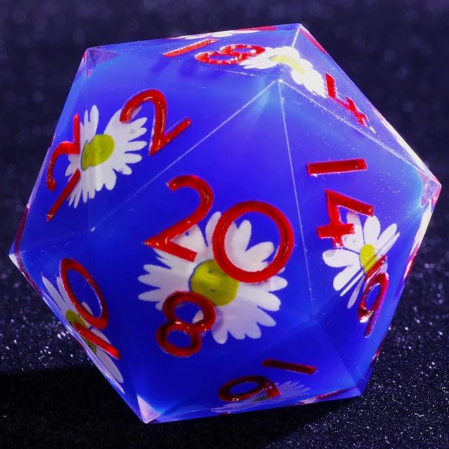 Close-up of a blue D20 decorated with white daisies and red numbers.