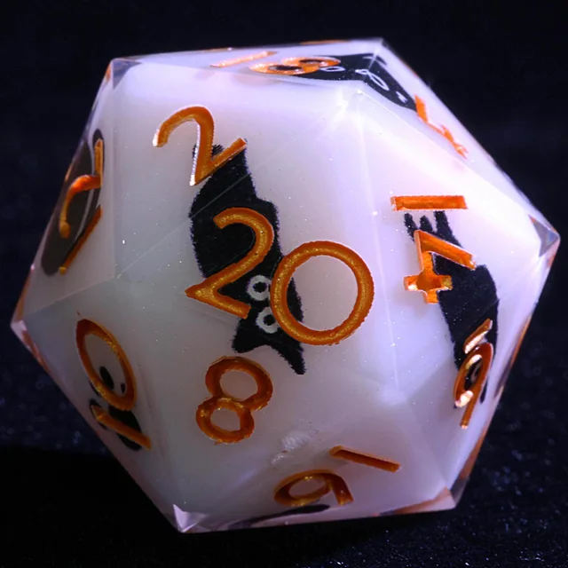 Close-up of a pale D20 with a black cat design and orange-gold numbers.