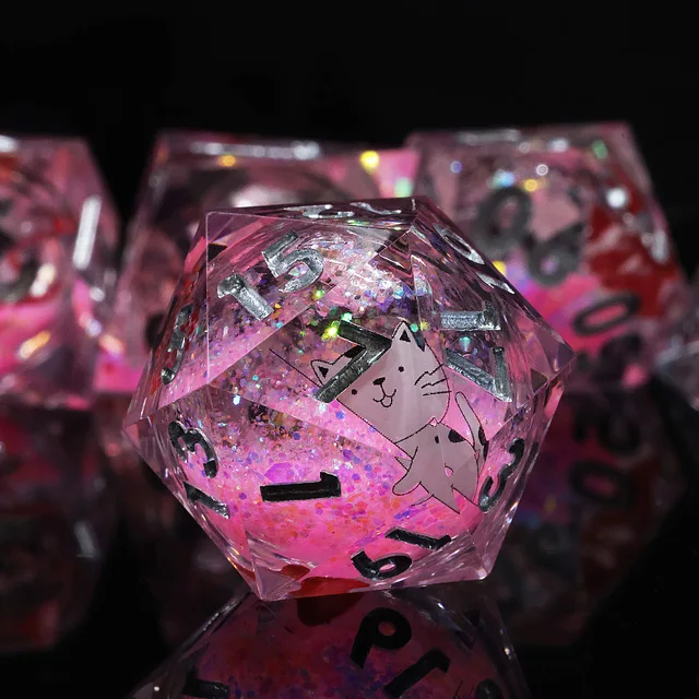 Close-up of a transparent pink die with a white cat illustration and silver numbers.