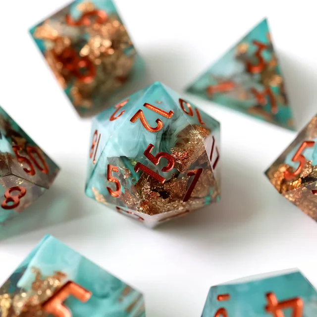 Close-up of the turquoise and gold-flake D20 with copper-orange numbers.