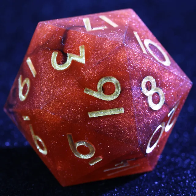 Close-up of a shimmering red D20 with gold-toned numbers.
