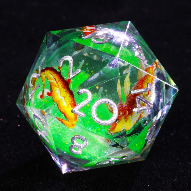 Close-up of clear D20 with green core, orange fish and silver numbers.