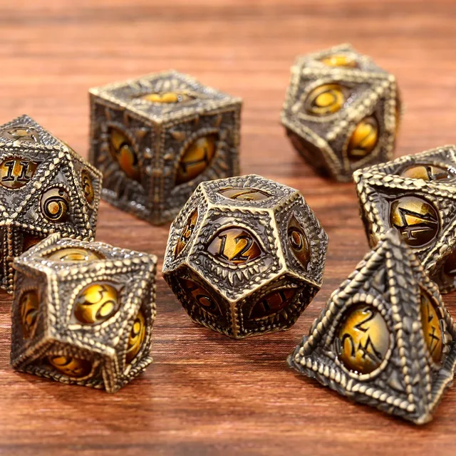 Antique-bronze polyhedral dice with amber-gold numbered faces and raised scale-like borders, shown with a black drawstring bag bearing a gold dragon graphic.