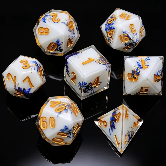 White polyhedral dice with blue floral patterns, gold-coloured numbers and clear-looking outer edges.
