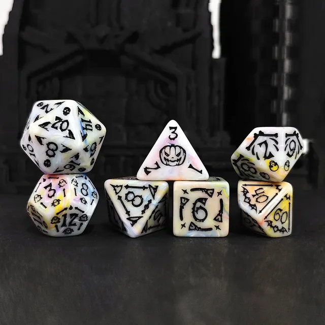 Seven creamy white polyhedral dice with pastel swirls, black numbers and Halloween-style pumpkin, skull, bat and bone details.